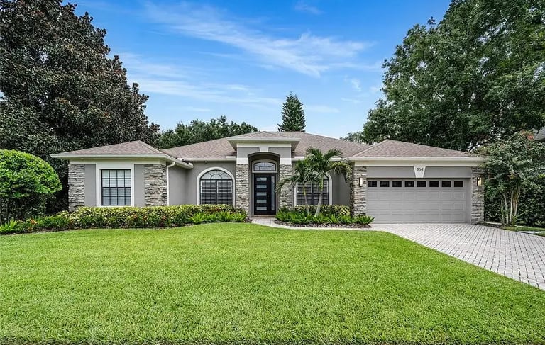 Exterior of a single-story home with a front lawn, stone accents, and an attached garage.