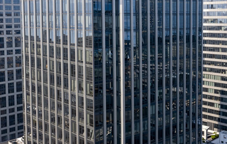 A high-angle professional architectural photograph of a futuristic glass skyscraper in a North American / US financial district. The scene is bathed in clean, bright daylight with deep navy and silver reflections on the glass. The composition is minimal and elegant, conveying a sense of world-class sophistication and technological leadership.