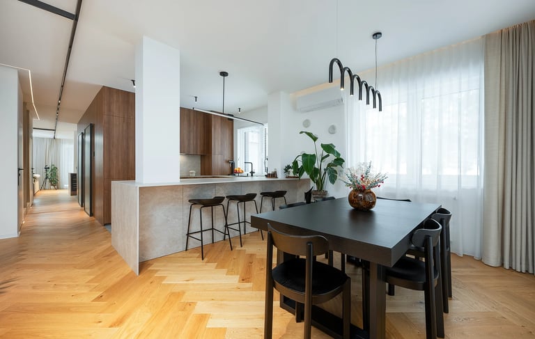 Nowoczesna kuchnia z wyspą i stołem jadalnym, drewniana podłoga, duże okno z zasłonami