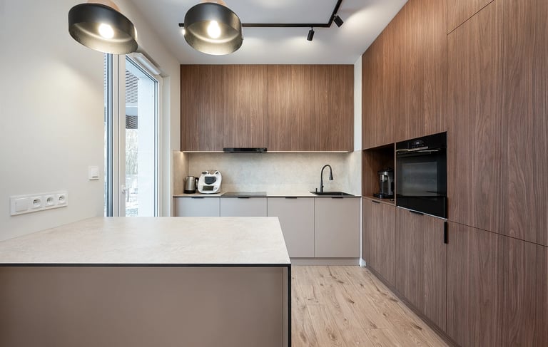 Nowoczesna kuchnia z drewnianą zabudową, wyspą kuchenną, piekarnikiem i zlewem.