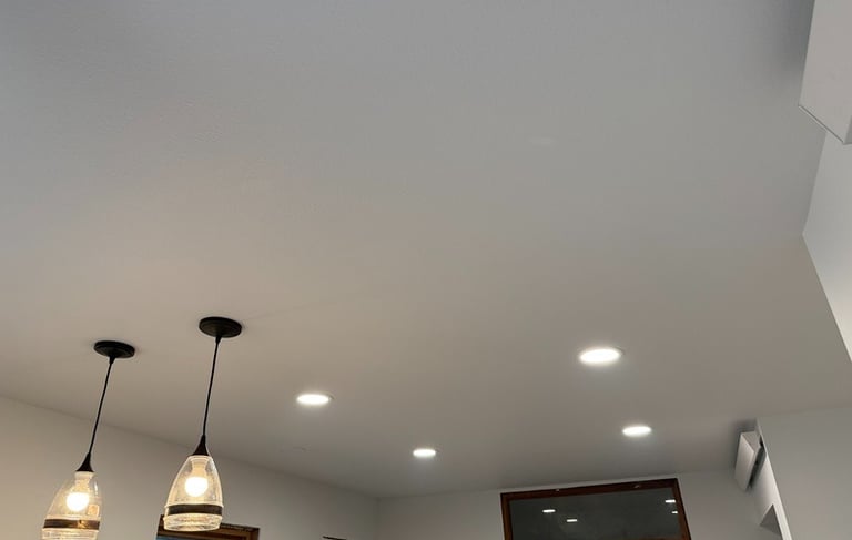 Modern white kitchen ceiling featuring recessed LED lights and two glass pendant light fixtures.
