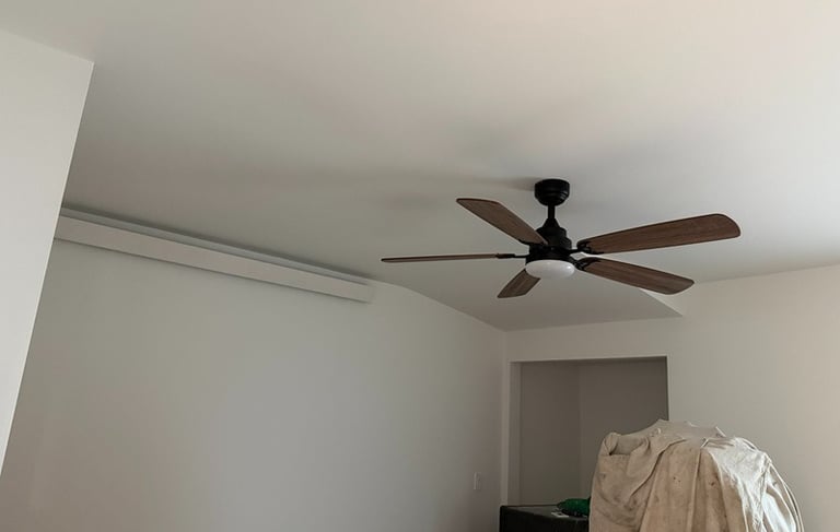Modern 5-blade wooden ceiling fan with integrated light installed in a white room.