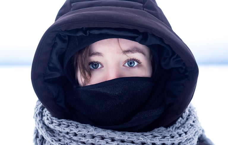 Portrait d'une femme portant une veste noire et un foulard autour du cou dans un décor de neige