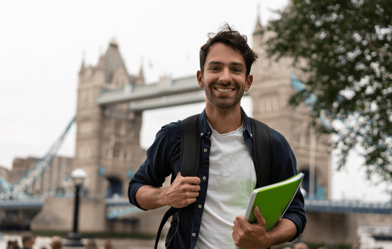 İngiltere'de Londra Köprüsünün önünde bir öğrenci değişim programı öğrencisi gülümsüyor