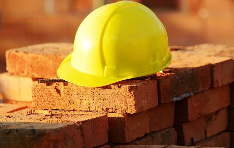a yellow hard hat with a yellow hard hat on top of a pile of bricks