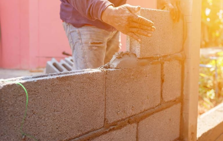 a man is building a brick wall with a cement block wall