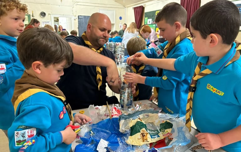 Beaver Scouts working with a leader to fill plastic bottles with eco-bricks made of plastic waste.
