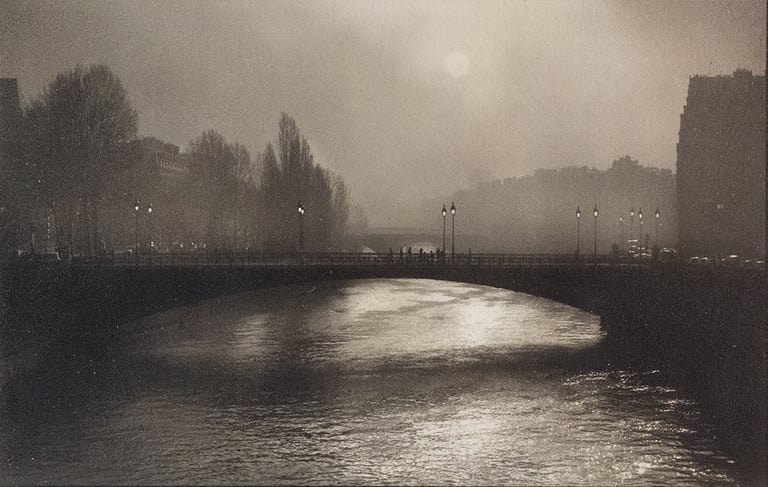 Atmospheric black and white photography of a foggy bridge over the Seine River in Paris.