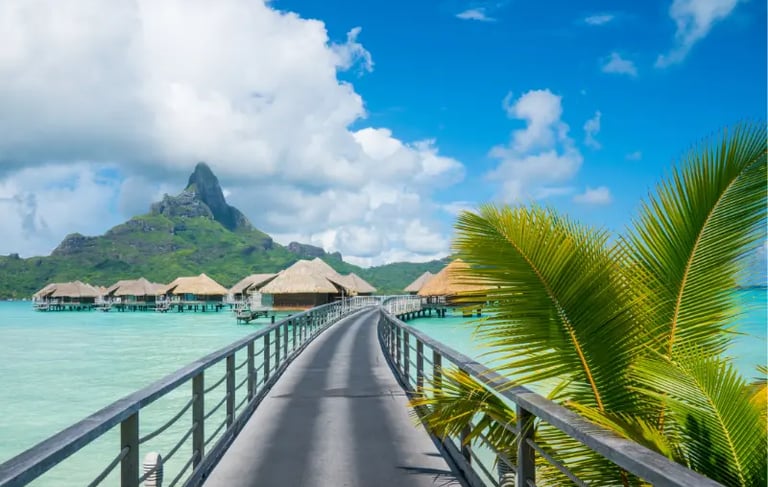 Luxury overwater bungalows in Bora Bora with a walkway over turquoise water and Mount Otemanu view.