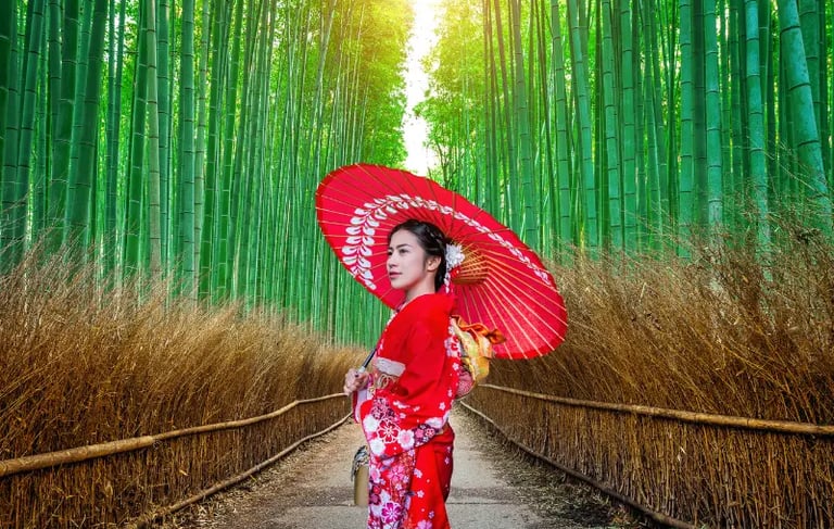 A woman in a red Japanese kimono holding a red umbrella in the Arashiyama Bamboo Grove in Kyoto.