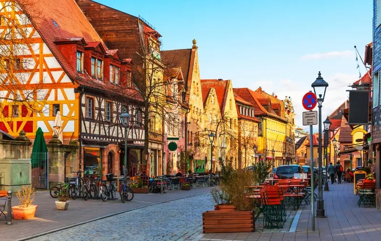 Charming cobblestone street in Nuremberg, Germany, featuring traditional half-timbered houses and outdoor cafes.