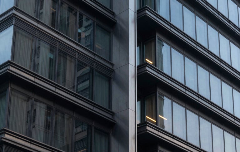 Close-up architectural photography of a modern building's facade, showing a blend of steel and glass in a Latin American urban setting, sophisticated evening lighting with colors of dark slate and blue grey, professional and sharp composition.