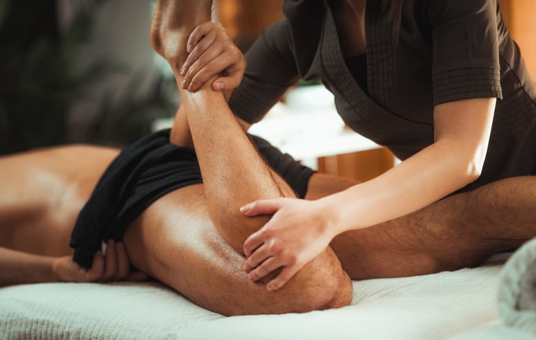 Female massage therapist performing sports massage on male client