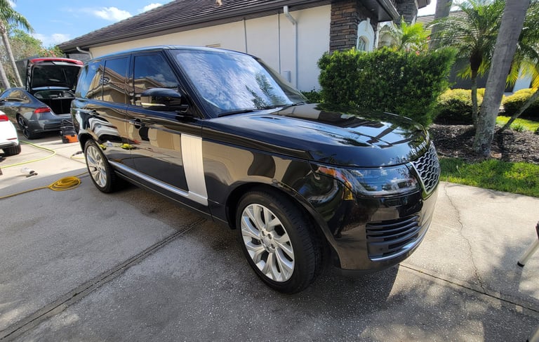 A black Ranger rover SUV ina tampa bay drive way surrounded by mobile detailing equipment