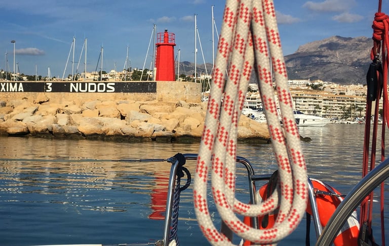 Port entrance with view of lighthouse and ropes on flat calm sea
