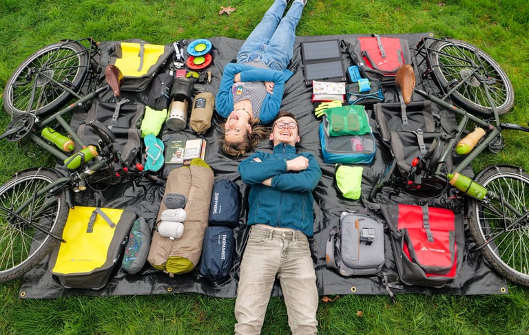 Couple d'aventuriers allongé avec tout leur matériel de voyage à vélo autour d'eux