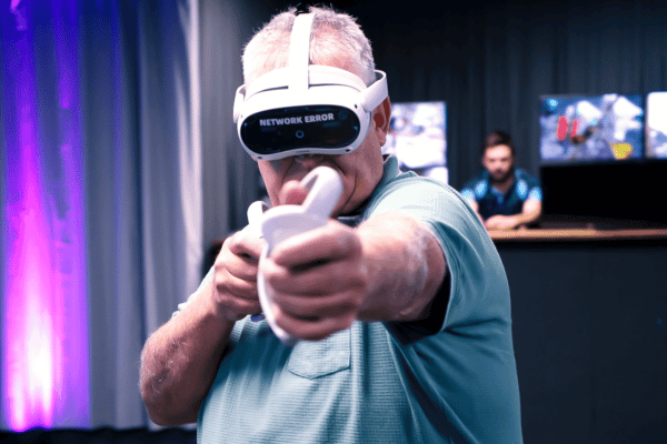 An older man in a blue shirt in a Pico 4 VR headset holding a VR game controller