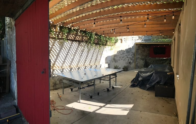 Outdoor garage man cave with bar, TV, and roof overhang performed by Golden Rule Construction
