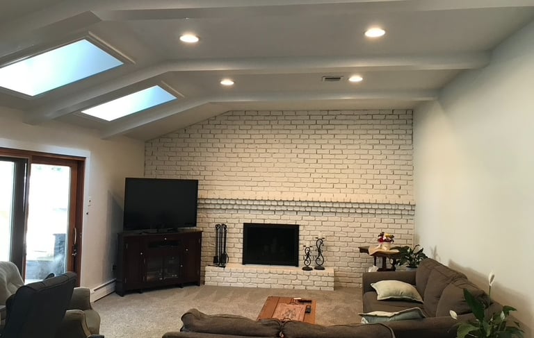 White painted brick fireplace updated living room renovation with skylights and recessed lighting