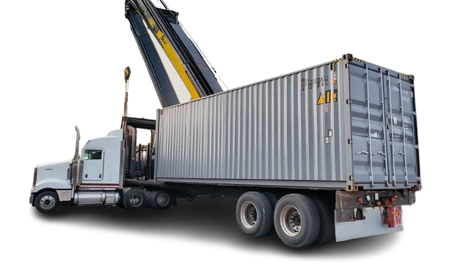 A heavy-duty reach stacker crane loading a grey metal shipping container onto a white semi-truck trailer.