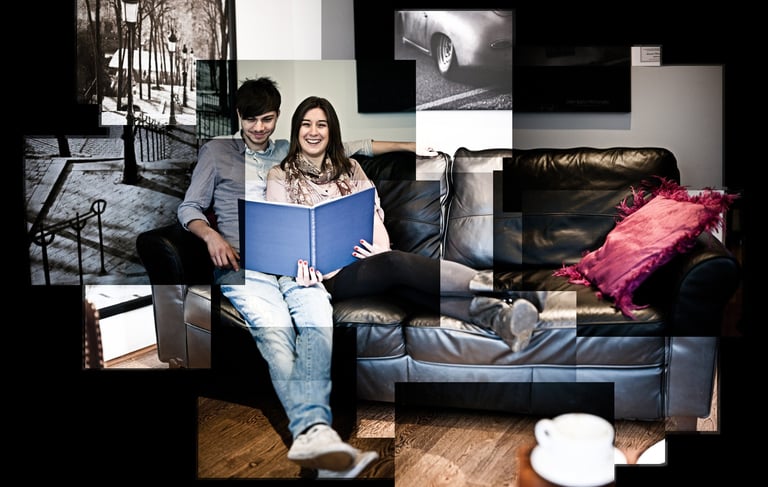 A joiner of a happy couple sat reading a book on a black leather sofa