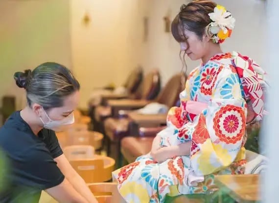 Kimono-dressed woman receiving foot spa treatment from therapist in Kyoto Japan