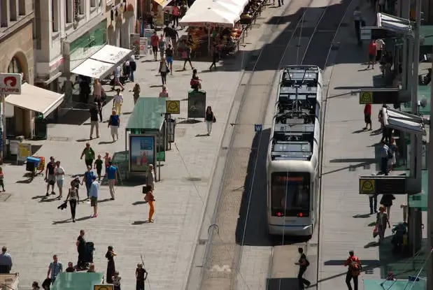 A tram passing through a busy pedestrian street in the historic center of Graz.