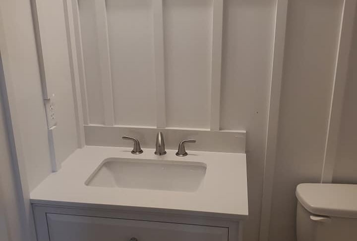 White bathroom vanity with board and batten wainscoting and silver faucet.