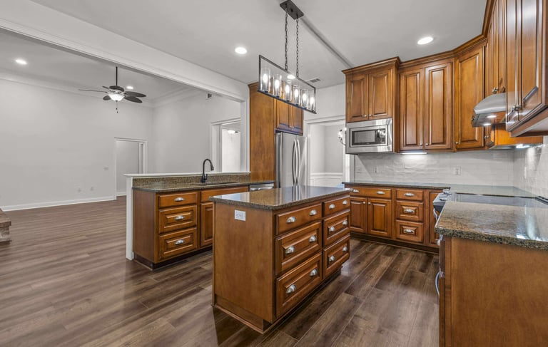 Modern kitchen with wood cabinets, granite countertops, a large island, and stainless steel appliances.