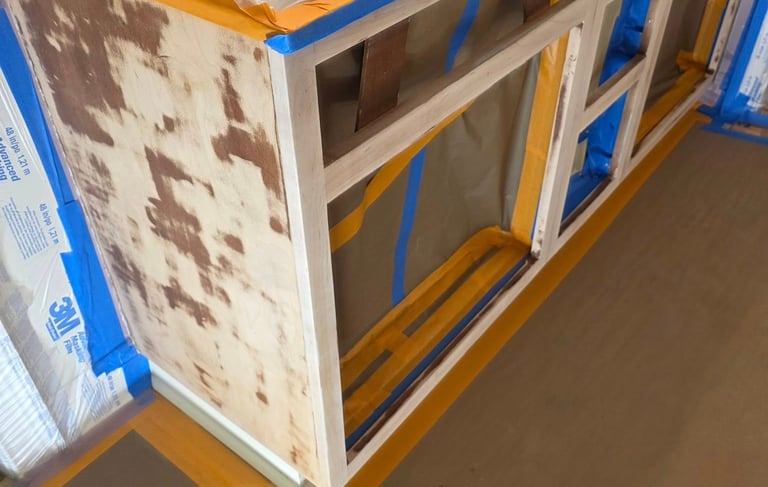 Sanded kitchen cabinets prepared for painting with 3M masking film and blue painter's tape.