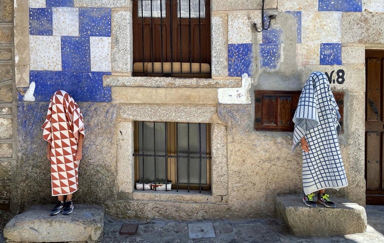 two people covered by blankets standing in front of a building