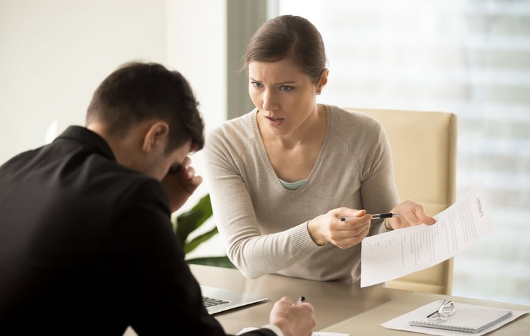 a man and woman sitting at a table with papers