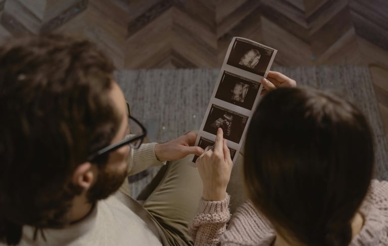 a man and woman sitting on a couch looking at photos of themselves