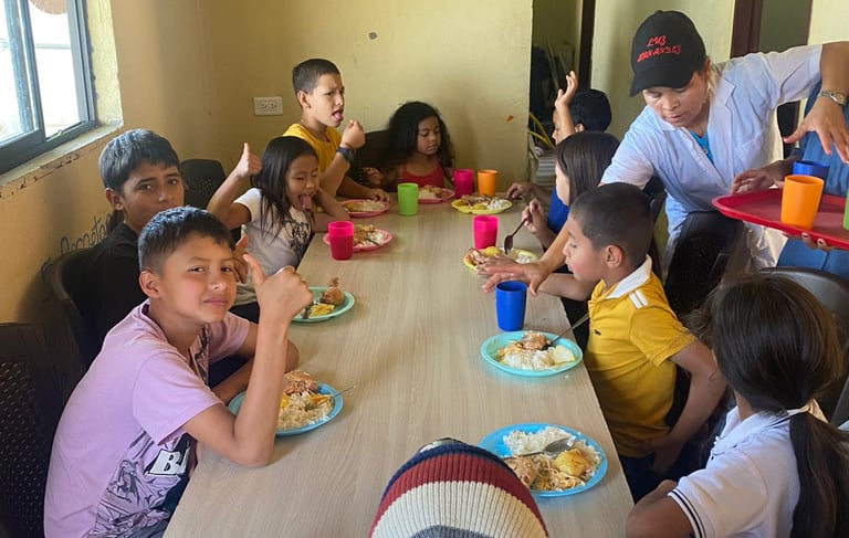 un grupo de niños y adultos sentados a la mesa almorzando