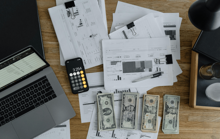 computer on table with financials and money