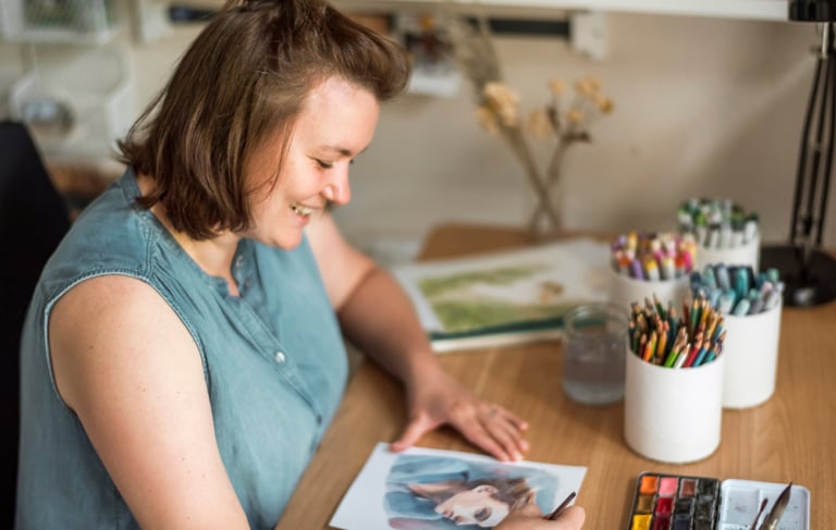 Sabrina zeichnet ein Portrait und lächelt