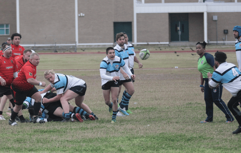a group of men playing rugby in a field passing scrum half