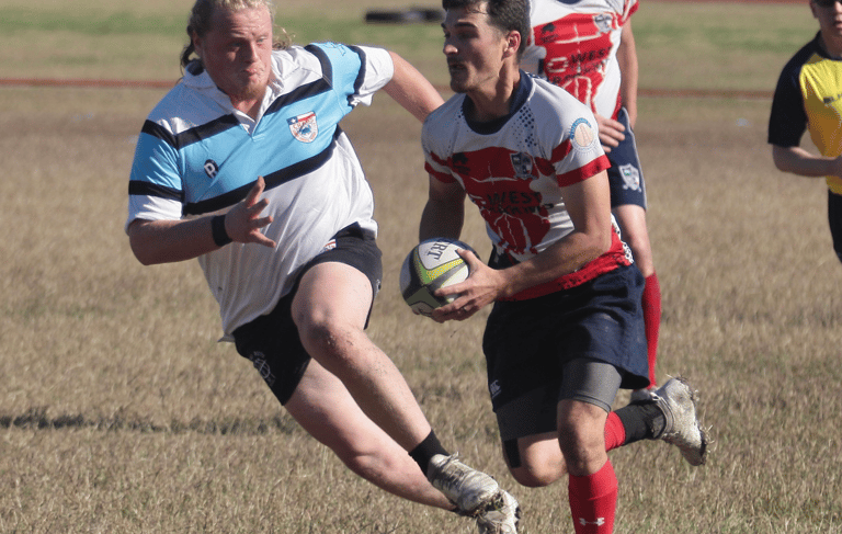 a man in a white shirt is playing rugby making a big tackle on texas teams