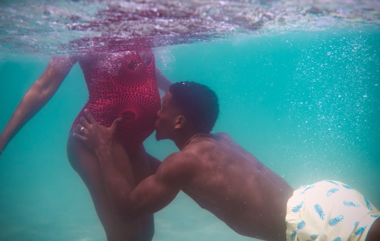 un homme embrasse sa femme enceinte sous l'eau