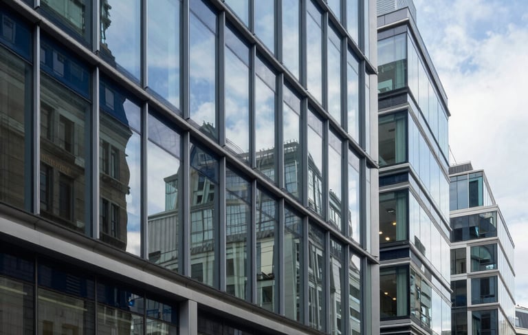 A professional and sophisticated photography shot of a high-end corporate office in London, United Kingdom. The scene features clean glass surfaces, steel blue accents, and a soft navy blue color palette. Modern architecture with natural light reflecting off polished surfaces, conveying a sense of integrity and financial excellence.