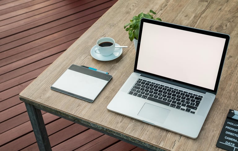 ordinateur portable ouvert sur une table avec une tasse à café et une ardoise veleda