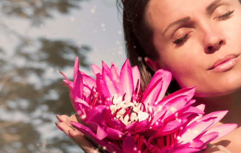 a woman holding a pink flower in her hands