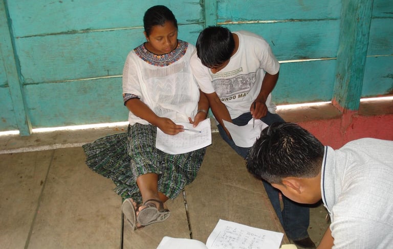 Phtoto of three K'eqchi' people studying the K'eqchi' language