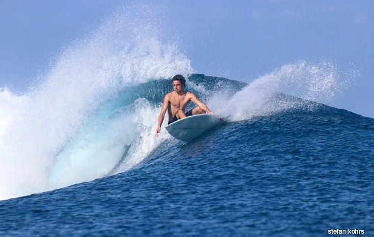 Surfer carving a sharp turn on a turquoise wave at a secret Mentawai spot
