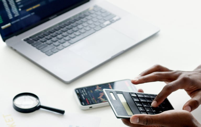 Pracownik dokonujący wyliczeń na laptopie w biurze.