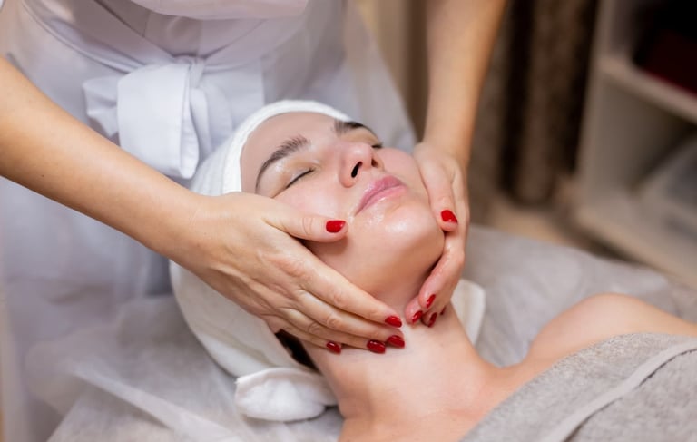 een vrouw met rode nagels dat een andere vrouw haar gezicht vast heeft om te masseren