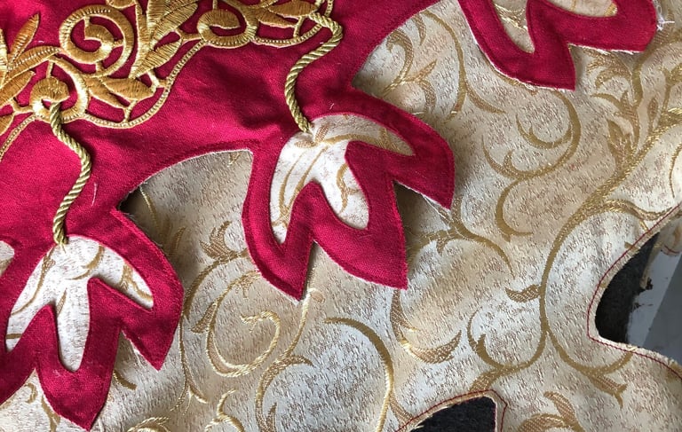 Photo de détails d'une tenue rouge et dorée avec des motifs dits de feuilles de chêne