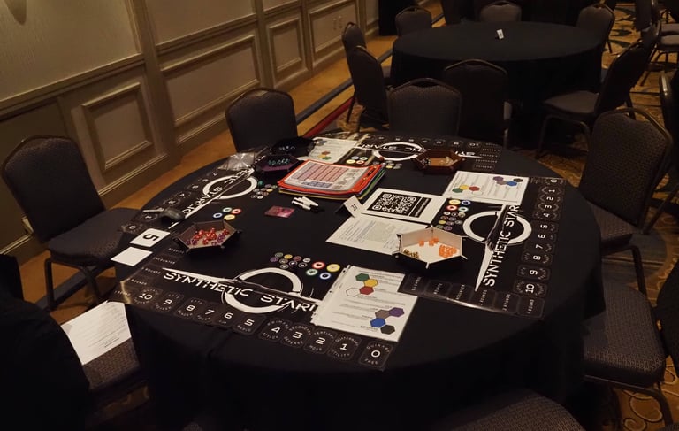 A table set up to run a game of Synthetic Starlight at Gen Con 2025. Dice, dice trays, and playmats.