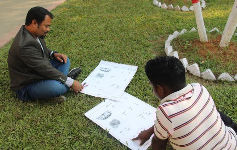a man sitting on the grass with a drawing of a car