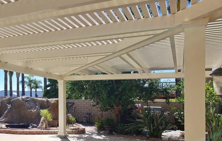 Hip ridge beam and mitered rafters on aluminum pergola in front of planter area.